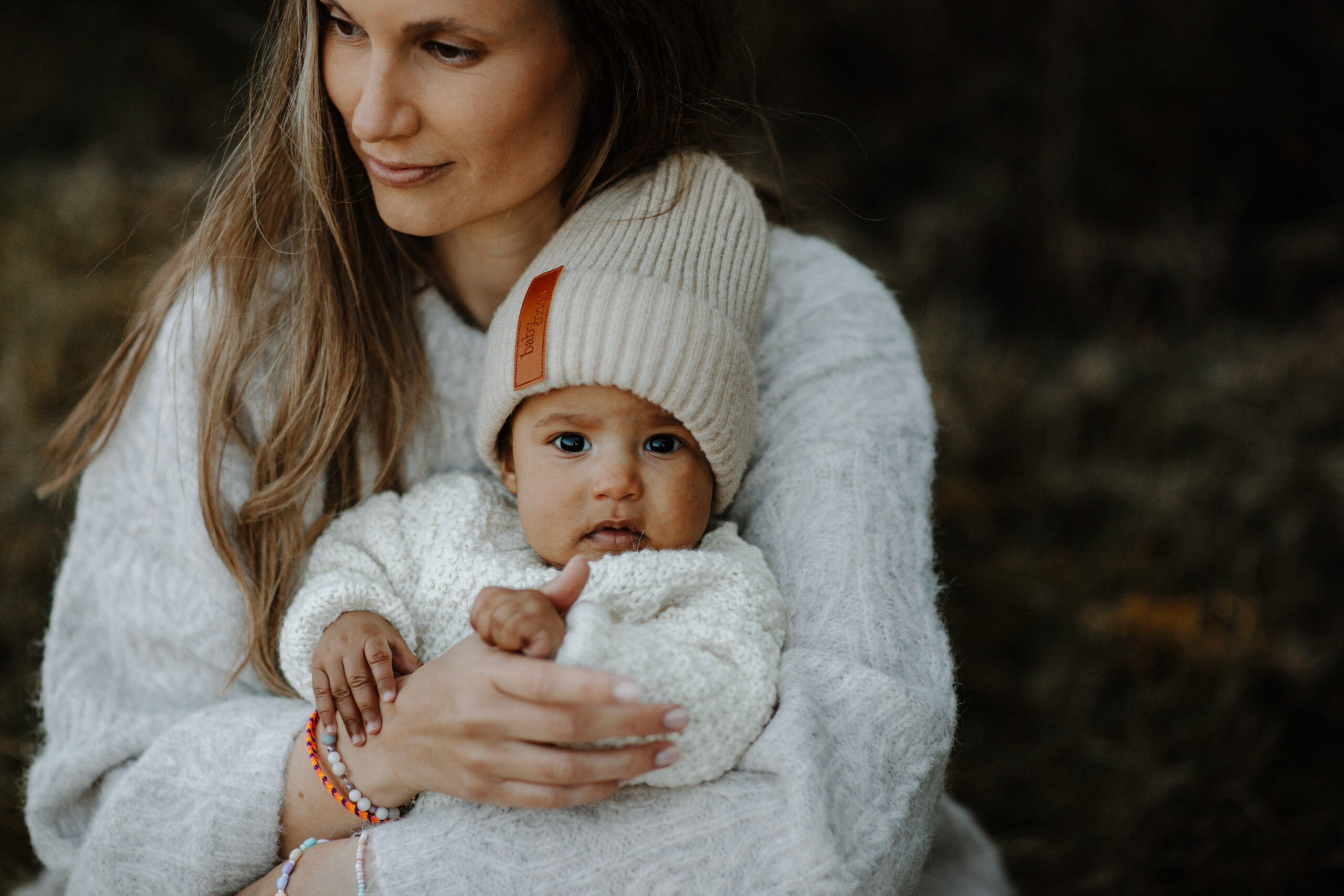 Mamma i vit stickad tröja håller sin bebis i famnen under en varm stund tillsammans